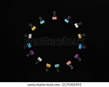 circle of multicolored paper clips with copy space in middle on black background