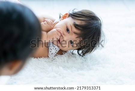 Selective focus cute lovely caucasian little baby girl, put a thumb in mouth, crawling on floor in cozy indoor home, playing with sister or sibling with copy space. Kid Development Concept
