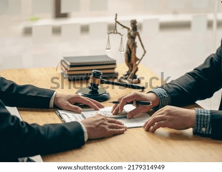 A meeting of professional business women and male lawyers working and discussing at the judge's hammered office with the scales of justice laid alongside the concept of law and consulting services.