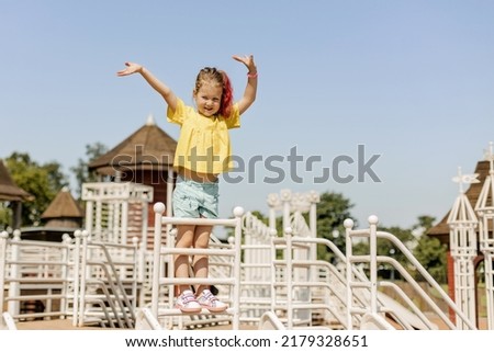 A charming little girl is having fun and playing on the playground. Happy childhood, summer time