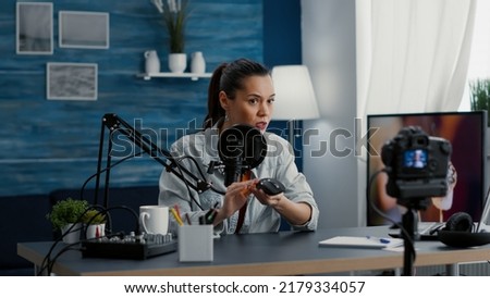 Tech influencer reviewing modern wireless mouse while presenting it to audience. Famous social media star doing recommendation video for electronic device while sitting at home studio desk.