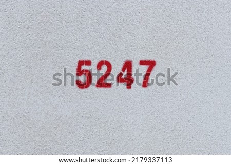 Red Number 5247 on the white wall. Spray paint.
