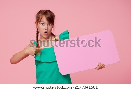 A cute laughing child girl is holding a signboard with an empty space for text. Advertising of childrens products and the announcement of discounts and sales