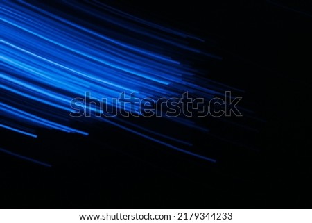Defocused neon light. Fluorescent rays. Sci-Fi radiance. Blur UV navy blue color glowing streak trail flare motion on dark black presentation abstract background.
