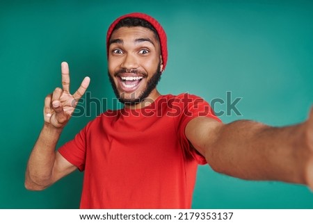 Excited African man gesturing while making selfie against green background