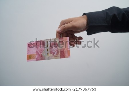 One hundred thousand rupiah dropped from man's hand on white background