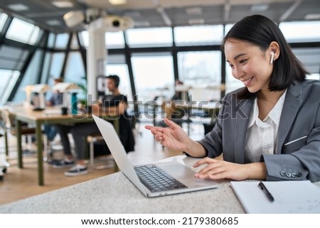 Young Asian business woman employee or executive manager using computer looking at laptop and talking leading hybrid conference remote video call virtual meeting or online training working in office. Royalty-Free Stock Photo #2179380685