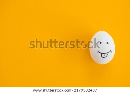Egg with funny face on yellow background