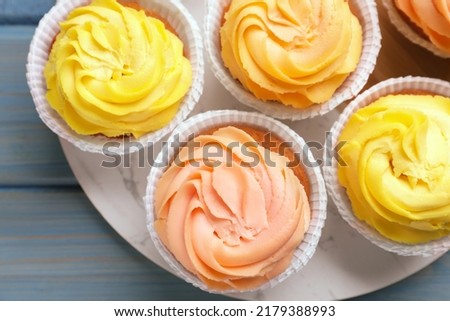 Stand with tasty cupcakes on light blue wooden table, top view Royalty-Free Stock Photo #2179388993