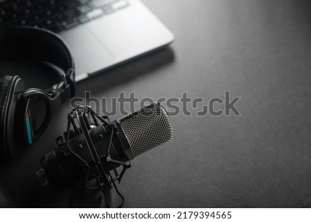 Studio microphone, studio headphones on a laptop on a gray background. Audio production, podcast, blogging, radio, journalism, presentation, software, home office.