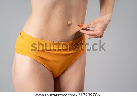Skinny belly after lifting, plastic surgery concept on gray background