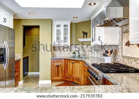 Modern house interior. White and brown kitchen room with shiny granite tops and mosaic back splash trim