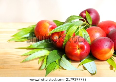 Nectarines with drops of water on a wooden table. A bunch of fresh fruit with leaves.  Smooth peaches. Royalty-Free Stock Photo #2179399799