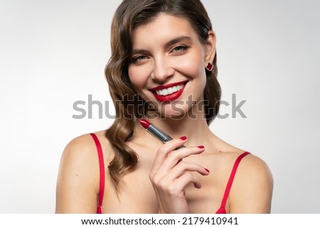 Elegant confident smiling woman preparing for date or festive dinner dressing up, trying new red lipstick on showing and recommending it to you isolated on white background