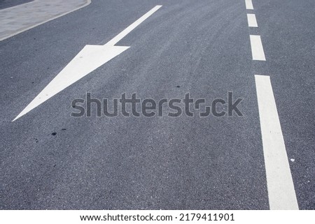 White arrow symbol in a straight direction on an asphalted avenue, transport concept