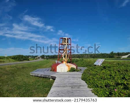 A large buoy sitting in the middle of a wooden walkway. There is a sign talking about the historical monument.