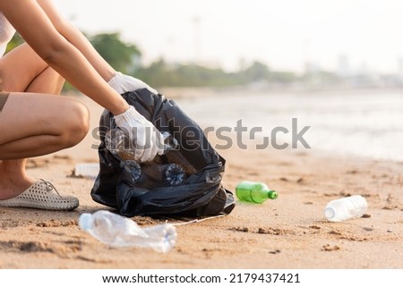 Volunteer woman picking plastic bottle into trash plastic bag black for cleaning the beach, female clean up garbage at sunset, Ecology concept and World Environment Day, Save earth concept Royalty-Free Stock Photo #2179437421