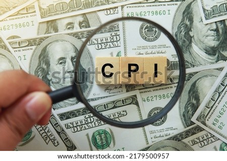 CPI, consumer price index symbol. hand holding magnifying glass investigating wooden block with words CPI, consumer price index on dollar bills. Business and CPI, consumer price index concept. Royalty-Free Stock Photo #2179500957