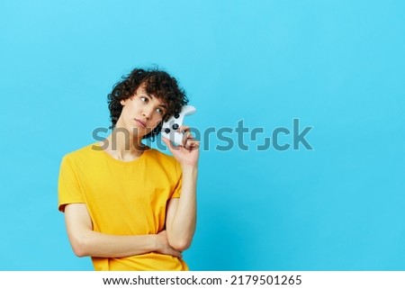 guy plays with joystick in yellow t-shirts blue background