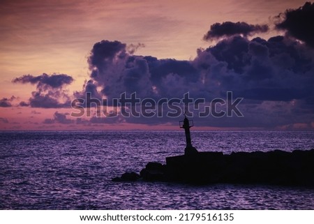 Lighthouse tower standing at the entrance of Marina da Calheta. Evening coastal landscape. Madeira, Portugal
