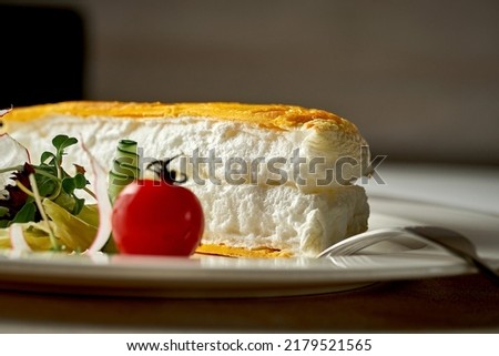 A tall egg omelet with lettuce on a white plate. Selective focus. Noise in post-production