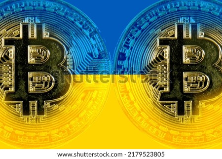 Holds a physical version of Bitcoin and the Ukrainian flag. Conceptual image of Ukraine's cryptocurrency and blockchain technology. Double exposure creative bitcoin symbol hologram.       