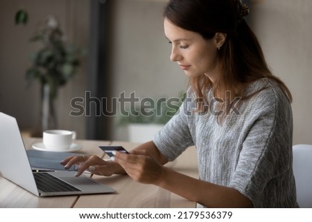 Young Caucasian woman sit at table make online payment or purchase using secure web banking system on computer, millennial female shopping on internet, pay bills with credit card on laptop on web