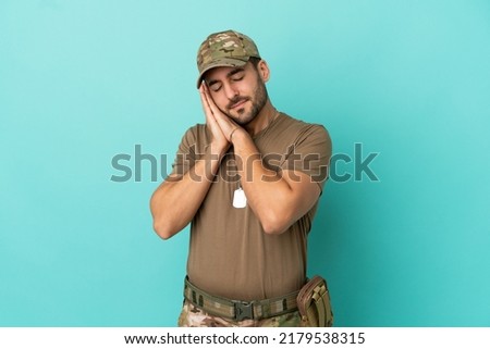 Military with dog tag over isolated on blue background making sleep gesture in dorable expression