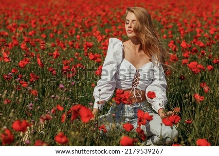 Young beautiful woman with long hair in a poppy field
