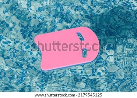 Safe pool training aid float foam board tool. Pink Swimming kickboard on blue water surface of swim pool. Mockup, copy space for text or design. Water sport, active lifestyle Royalty-Free Stock Photo #2179545125