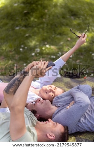 Summer, holidays, vacation, technology and happiness concept - group of smiling people in sunglasses taking picture with smartphone in park