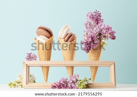 Various macaroon cookies in ice cream cones and lilac flowers