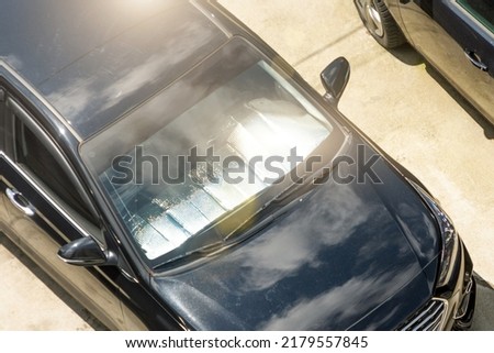 Protective reflective surface under the windshield of the passenger black car parked on a hot day, heated by the sun's rays inside the car Royalty-Free Stock Photo #2179557845
