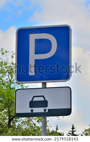 A road sign allowing parking along the curb on a summer day