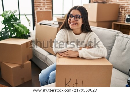 Young hispanic woman smiling confident leaning on package at new home