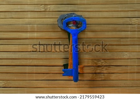 Old blue key on a wooden background.