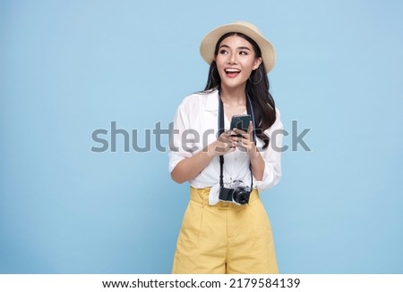Happy young Asian tourist woman using smartphone application going to travel on holidays isolated on blue background.