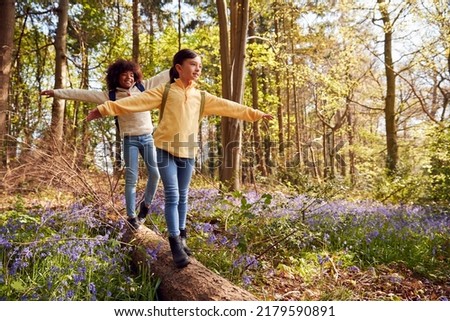 Two Children Walking Through Bluebell Woods In Springtime Balancing On Log Royalty-Free Stock Photo #2179590891