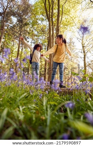 Low Angle Shot Of Two Children Walking Through Bluebell Woods In Springtime Balancing On Log Royalty-Free Stock Photo #2179590897