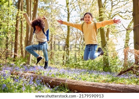 Two Children Walking Through Bluebell Woods In Springtime Jumping Over Log Royalty-Free Stock Photo #2179590913