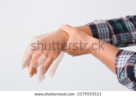 Hands of mature man with Parkinson syndrome on light background Royalty-Free Stock Photo #2179593511