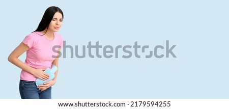 Young woman suffering from menstrual cramps on light blue background with space for text Royalty-Free Stock Photo #2179594255