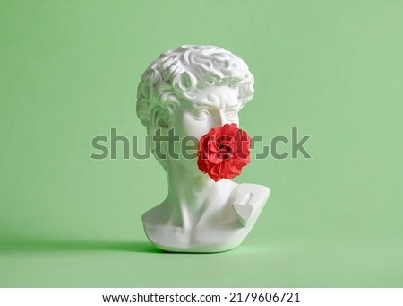 Michelangelo's David head sculpture with rose flower closed mouth. Minimal pastel creative kiss and love concept. Royalty-Free Stock Photo #2179606721