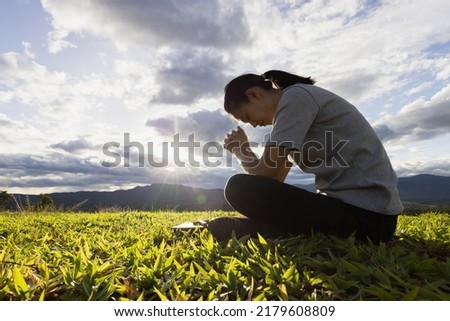 Woman praying for thank god praying with her hands together to think of a loving God, we praise God with light flare in the green nature. Royalty-Free Stock Photo #2179608809