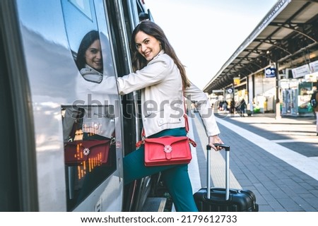 Young business woman standing on train door peeking out looking for somebody in railway station - Potrait of beautiful traveler woman getting on the train - Travelling concept Royalty-Free Stock Photo #2179612733