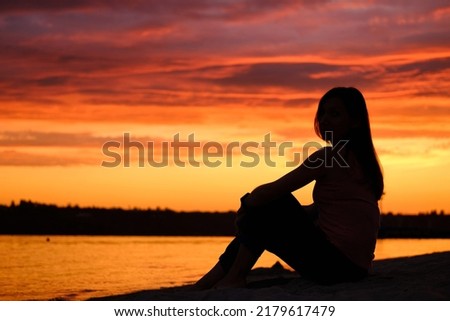 Alone woman sitting watching the sunset sunrise. Royalty-Free Stock Photo #2179617479