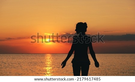 silhouette of woman on the beach at sunset. Young woman relaxing in summer sunset sky outdoor. People freedom style.