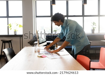 Creative biracial young businessman working at computer desk in office. Unaltered, creative business, workplace, photography themes, technology.