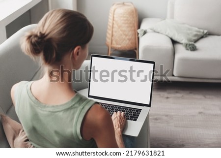 Young woman working at home, using laptop computer with blank white screen display mockup. Student girl looking at laptop screen. Online shopping, web site, working from home, online learning studying