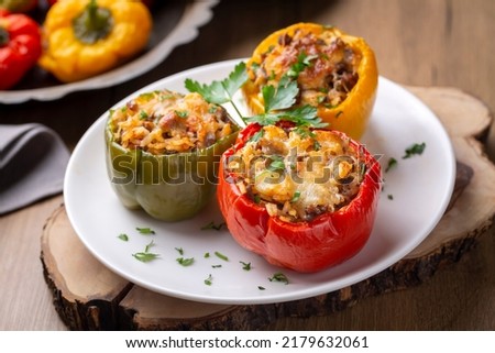 Stuffed peppers, halves of peppers stuffed with rice, dried tomatoes, herbs and cheese in a baking dish on a blue wooden table, top view. (Turkish name; biber dolmasi) Royalty-Free Stock Photo #2179632061